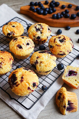 Close-up of vanilla muffins with blueberries on metal mesh tray and cotton towel near blueberries on grey background