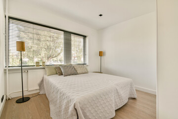 A serene and stylish bedroom showcasing contemporary design, featuring large windows that invite natural light and a clean aesthetic.