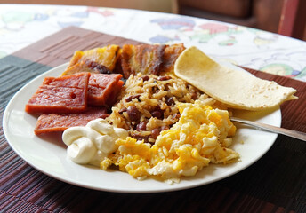 Traditional Costa Rican breakfast, rice and beans, called Gallo Pinto with eggs, tortilla, sausage and plantain.