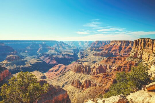 Breathtaking panoramic view of a vast canyon, showcasing layered rock formations, a winding river, and desert vegetation under a clear blue sky