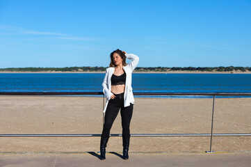 Young and beautiful blonde woman is leaning on the railing of the promenade at the mouth of the...