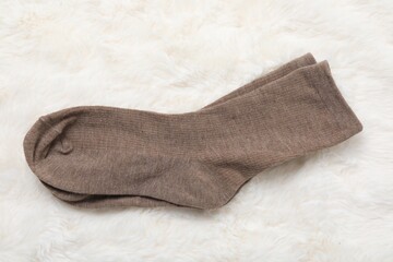 Pair of soft socks on white faux fur, top view