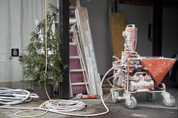 dirty plastering or stucco spraying machine, applying plaster, mortar, or other wall-coating materials onto surfaces quickly and evenly in constructions. large-scale wall finishing.