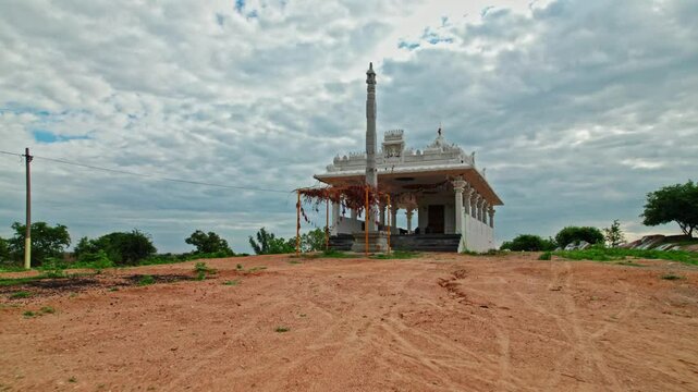 newly constructed Hindu temple with dwajasthambam and rainy clouds at day time, low angle, push in, drone shot, 4k.