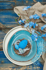 Easter table setting with eggs, bird's nest and blooming branch. Traditional festive symbols