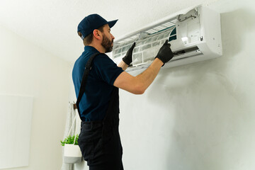 Technician cleaning air conditioner filter during maintenance service