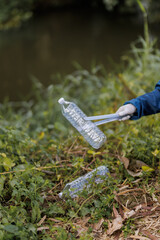 A cheerful Asian volunteer with a bright smile is actively helping to clean up litter along a public canal.
