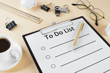to do list on clipboard with office supplies, isolated on beige background