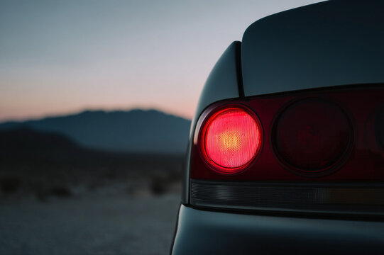 car taillight glows in twilight of desert, creating serene and mysterious atmosphere - Powered by Adobe