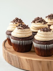 Group of chocolate cupcakes on a wooden cake stand. the cupcakes are arranged in a row and are topped with a generous swirl of white frosting.