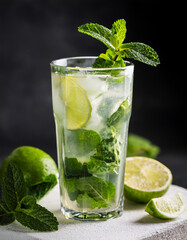 Fototapeta premium Glass of mojito with lime, mint leaf, white stone platform. Alcoholic cocktail. Delicious beverage