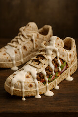 Sneakers made of lavash, inside the sneakers there is a filling of meat with sauce and vegetables, and sauce runs down the lavash sneakers