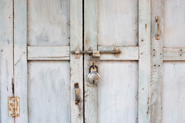 Old weathered door locked with a padlock, white shabby color, India

