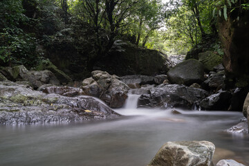 Fototapeta premium waterfall falling and flowing rapidly on rocks. water with motion blurr. slow shutter speed photography technique