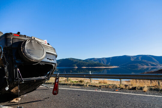 Crashed car flipped onto roof on rural road with copy space