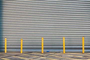 Industrial metal roller door with yellow posts blocking entry