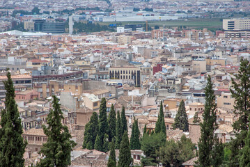 Obraz premium Dense cityscape with trees in foreground, hazy background, Granada, Spain
