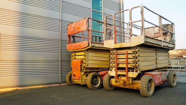 Two old and rusty industrial scissor lifts, essential for elevated work
