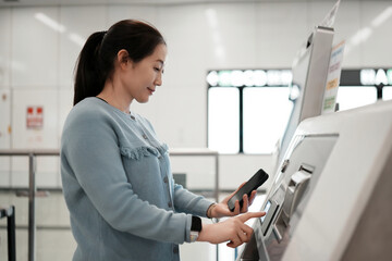 Young Woman Interacting with a Ticket Machine at a Station