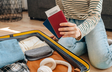 Young female traveler sitting on floor packing suitcase preparing for summer vacation trip