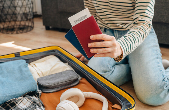 Young female traveler sitting on floor packing suitcase preparing for summer vacation trip