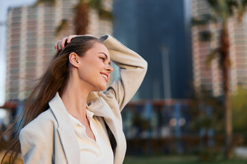 Fototapeta premium Confident businesswoman smiling in a modern urban setting, dressed in stylish office attire, showcasing professionalism and elegance, with a blurred city backdrop.