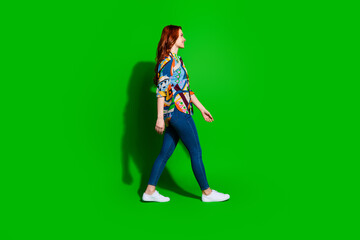 Stylish young woman walking confidently on a green background showcasing vibrant fashion