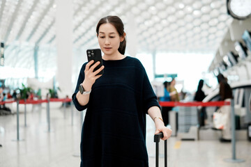 Young Woman Checking Phone While Waiting at Airport Check-In