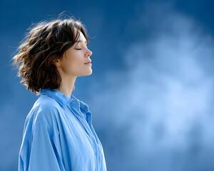 Serene woman with eyes closed, enjoying peaceful moment against a blue sky