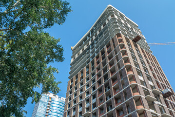 Fototapeta premium The exterior walls of the high-rise building are lined with decorative facade bricks. Technologies for the construction of high-rise buildings. The building's frame is made of reinforced concrete.