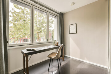 Bright, minimalist home office featuring a desk and chair by large windows, enhancing productivity with fresh greenery views.