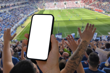 Cell phone with transparent screen in human hands. In the background, out of focus, a football...