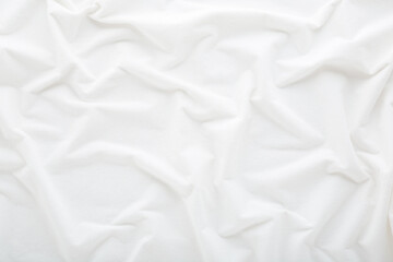 White wavy bed sheet background. Closeup. Top down view.