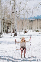 girl on a swing in a the snowy mountains