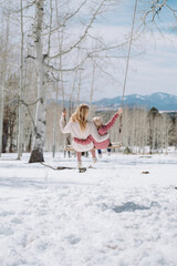 mother and daughter on a swing in a the snowy mountains