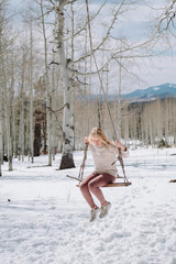 girl on a swing in a the snowy mountains