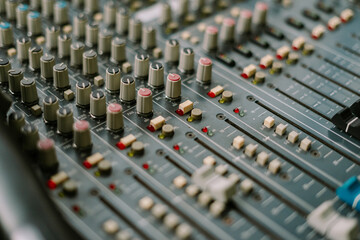 Close-up of professional audio mixing console surface with sliders knobs