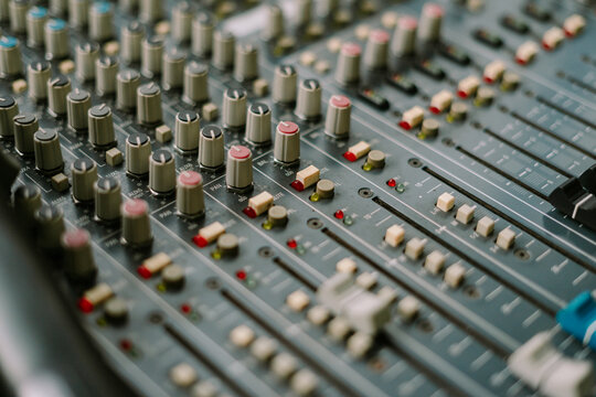 Close-up of professional audio mixing console surface with sliders knobs