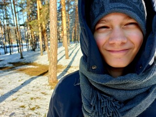 Portrait of a young boy in the wood on the cold day photo. Smiling Boy in Winter Forest. Close up people photography.
