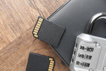 External hard drive, SD memory cards and combination padlock on wooden table, flat lay