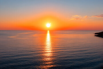 Fototapeta premium A breathtaking sunset over calm waters, showcasing vibrant hues of orange and pink, reflecting on the serene surface, perfect for travel enthusiasts.