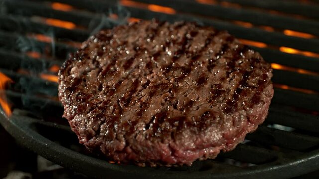 Super Slow Motion Shot of Flipping Hamburger Meat on Hot Grill with Flames and Embers at 1000fps.