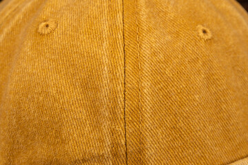 Detailed top view of a mustard yellow denim cap, showing two ventilation holes and center seam.
