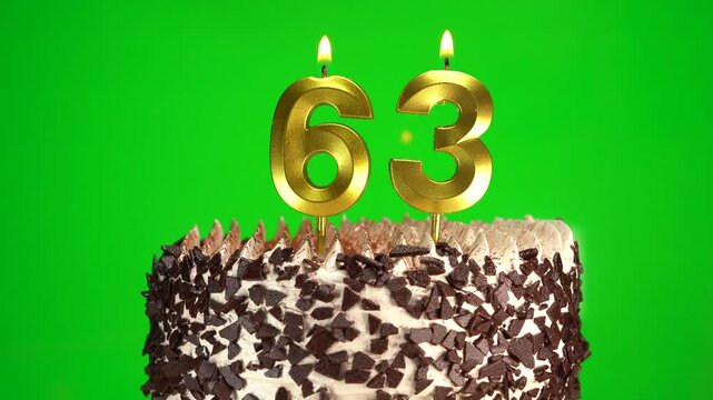 Burning candles number 63 on birthday cake against chroma key background. Sixty-third birthday. Birthday celebration
