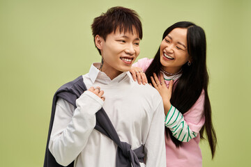 Stylish couple sharing laughter and joy in a vibrant green setting under soft lighting