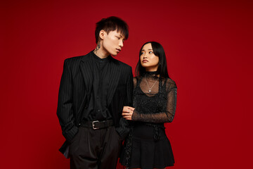 Stylish couple showcasing romance and elegance against a vibrant red backdrop in a modern setting