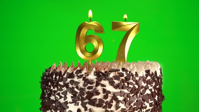 Burning candles number 67 on birthday cake against chroma key background. Sixty-seventh birthday. Birthday celebration