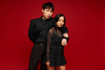 Stylish couple showcasing love and romance against a vibrant red backdrop in modern fashion