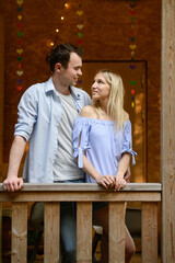 Man and woman standing on verandah of house, tenderly looking at each other, showing love and care....