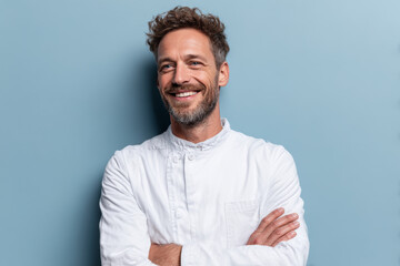 Positive middle-aged man in white shirt, minimalist portrait against light blue wall.